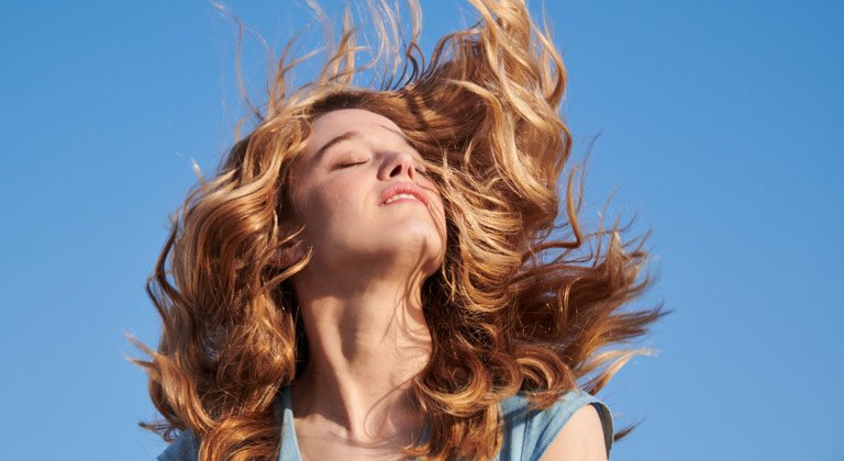 model swishing hair outside on blue sky background