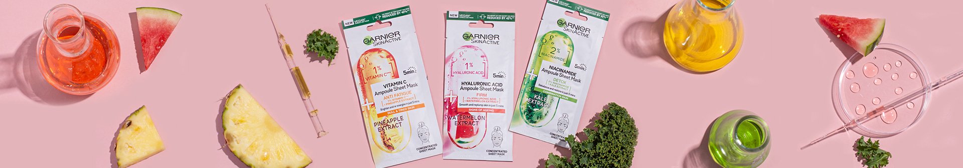 ampoule sheet masks with decorative ingredient assets laid on pink background