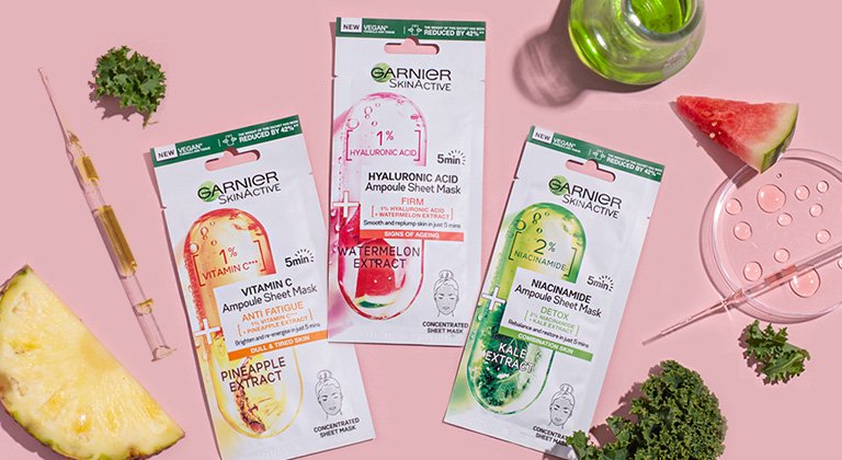 ampoule sheet masks with decorative ingredient assets laid on pink background