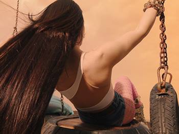 Back of heads and hair of two girls on swing.