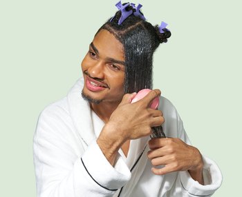 a curly-haired person using a comb with conditioner to detangle her curly hair