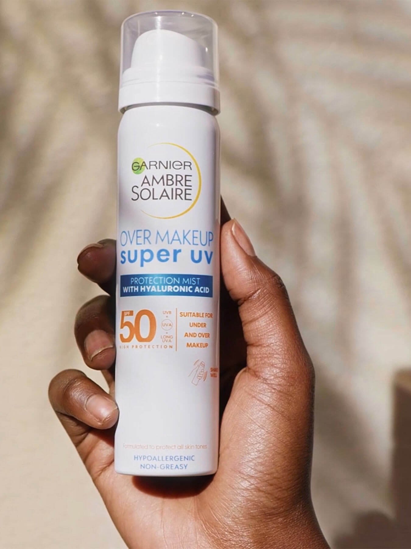 hand holding Ambre Solaire Super UV over makeup mist 